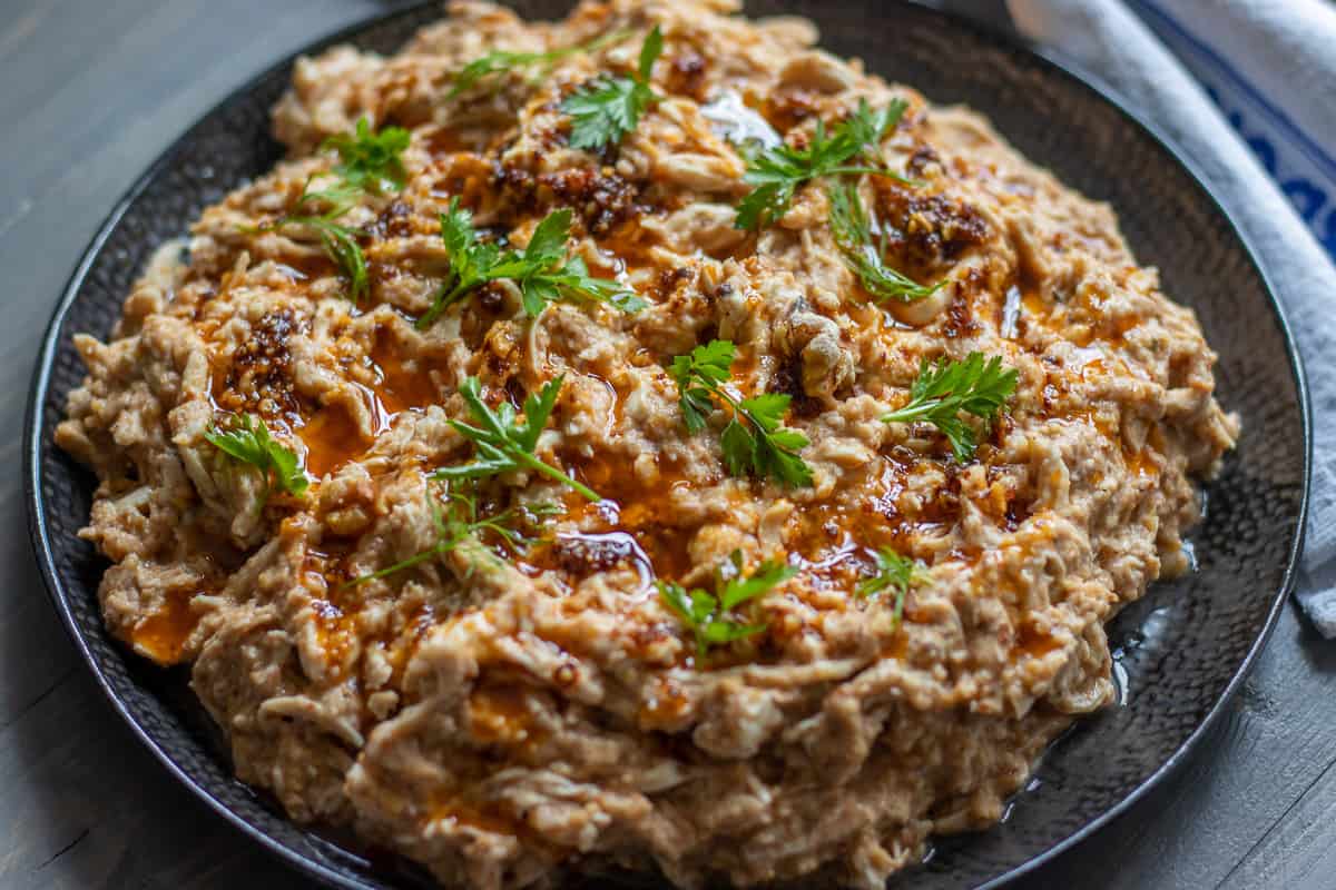 Cerkez tavugu plated in a bowl and garnished with chili oil.