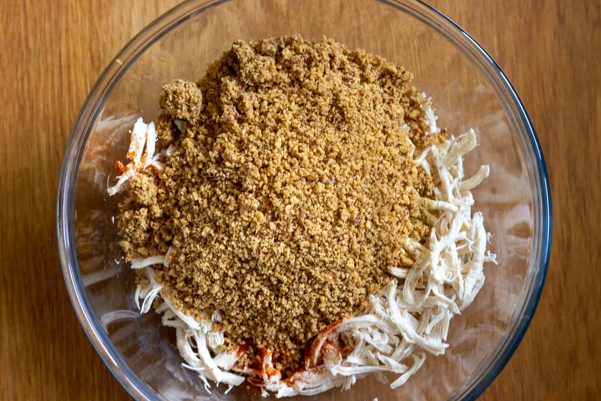 Shredded chicken pieces, walnuts, spices and soaked bread in a bowl