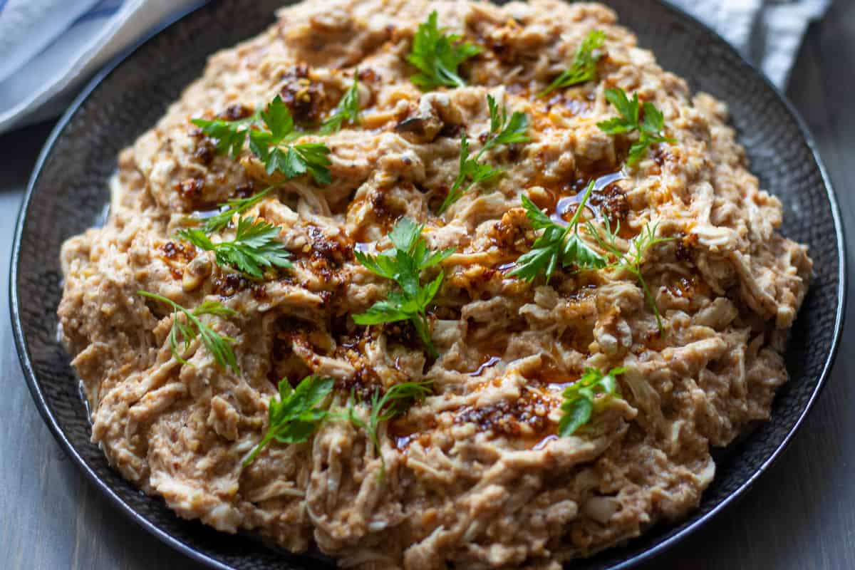cerkez tavugu plated and garnished with chilli oil and parsley
