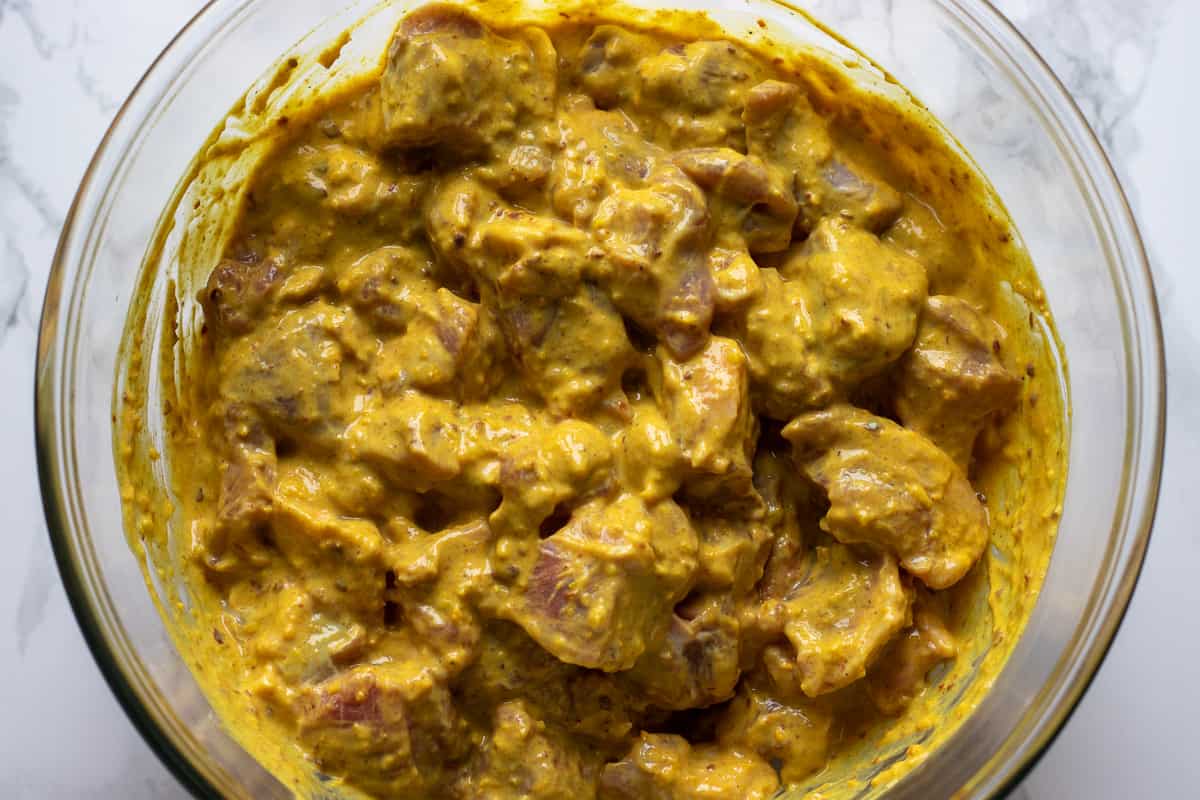 The cubed lamb pieces are stirred in the marinade