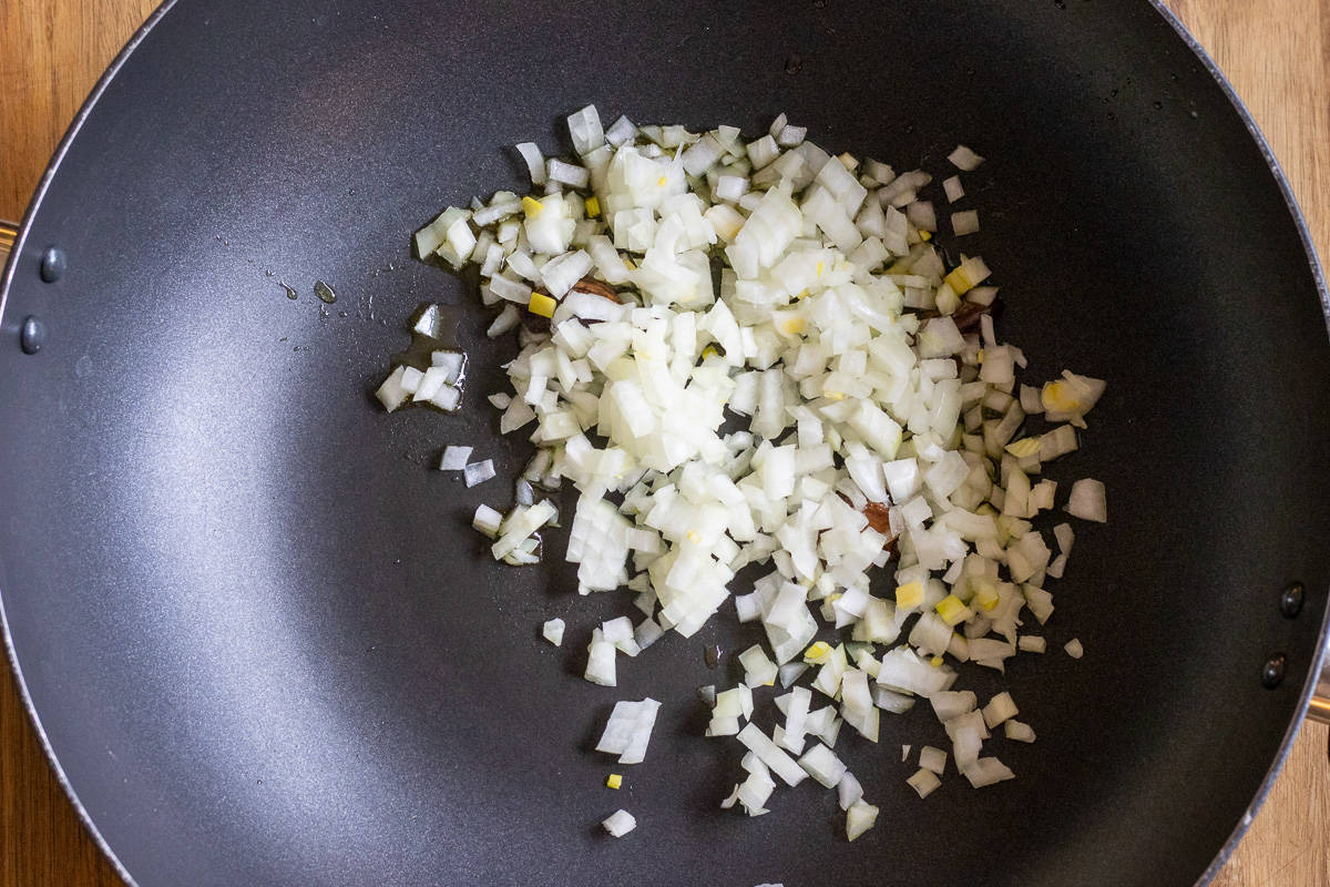 Chopped onions are in a pan for sautéing