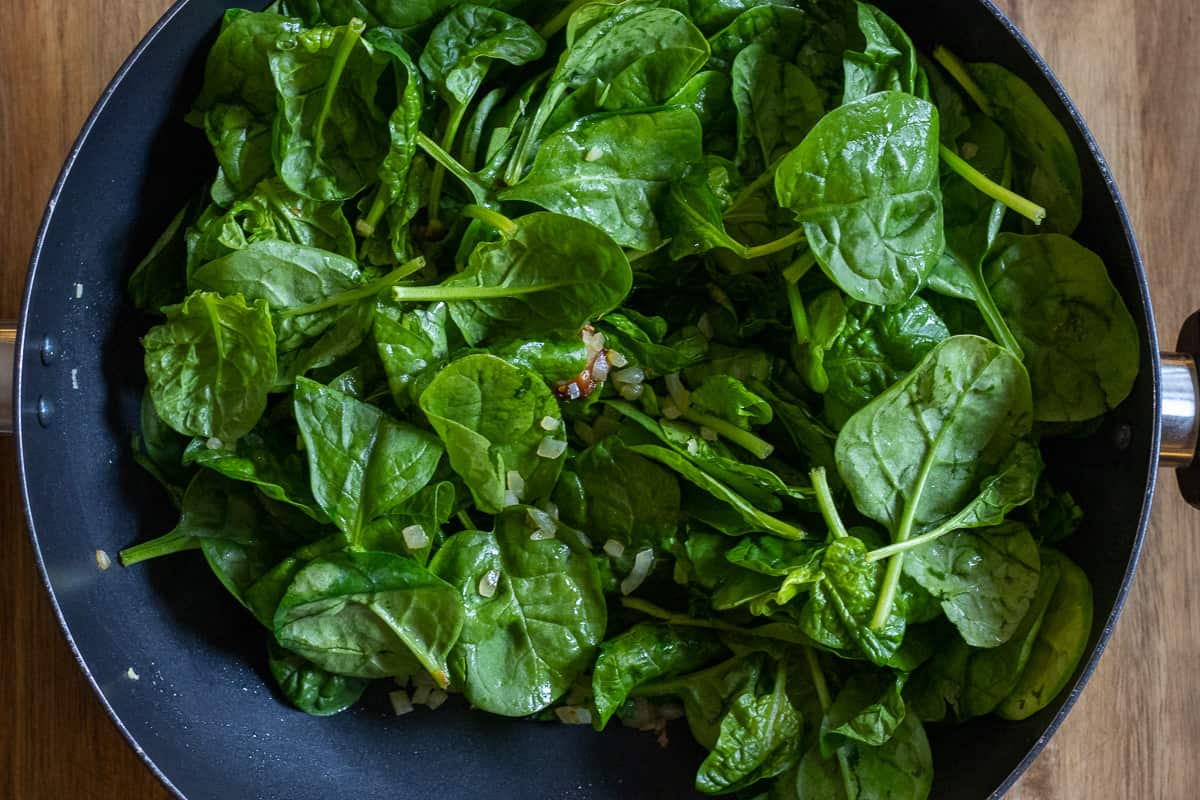 sautéing the spinach in wok with the onions