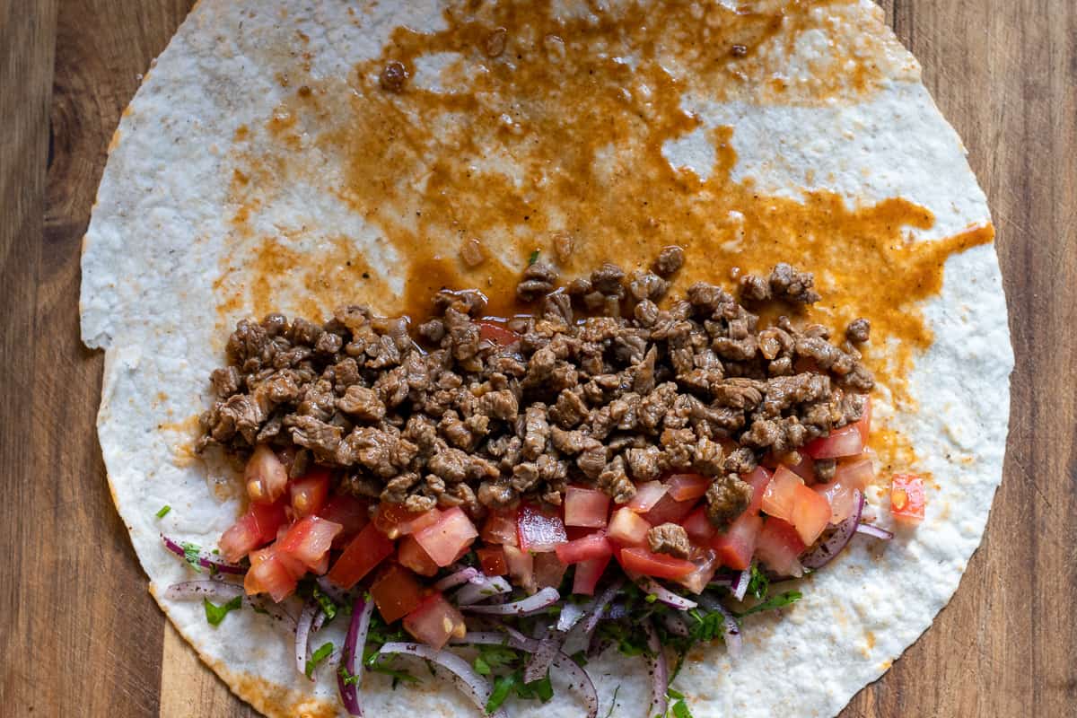 meat, tomatoes and onion salad is placed on one side of lavas