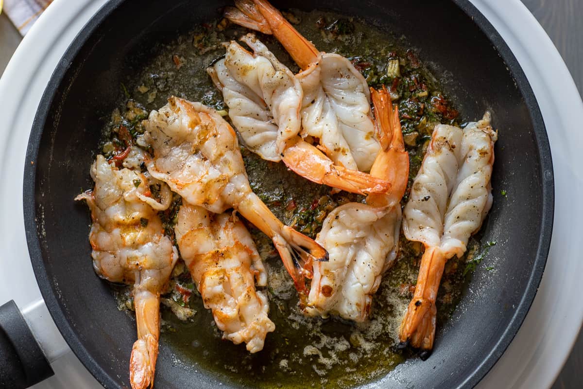 7 pieces of barbecued shrimp tossed in garlic butter sauce in a pan