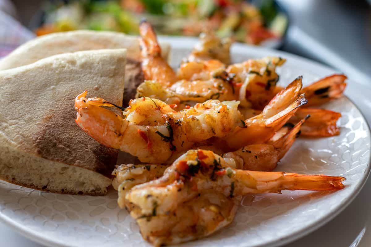 seven pieces of BBQ shrimp served with a piece of flatbread on the side