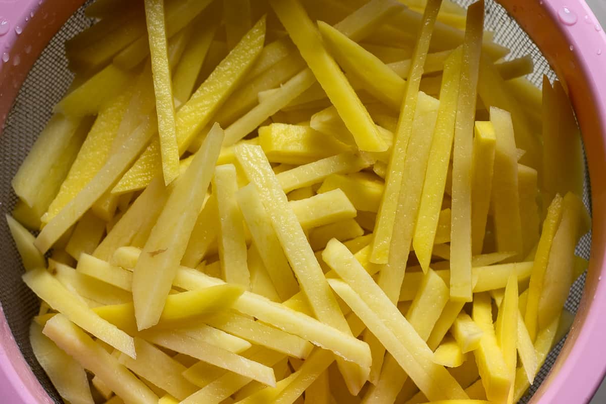 Matchstick potatoes are placed on a colander
