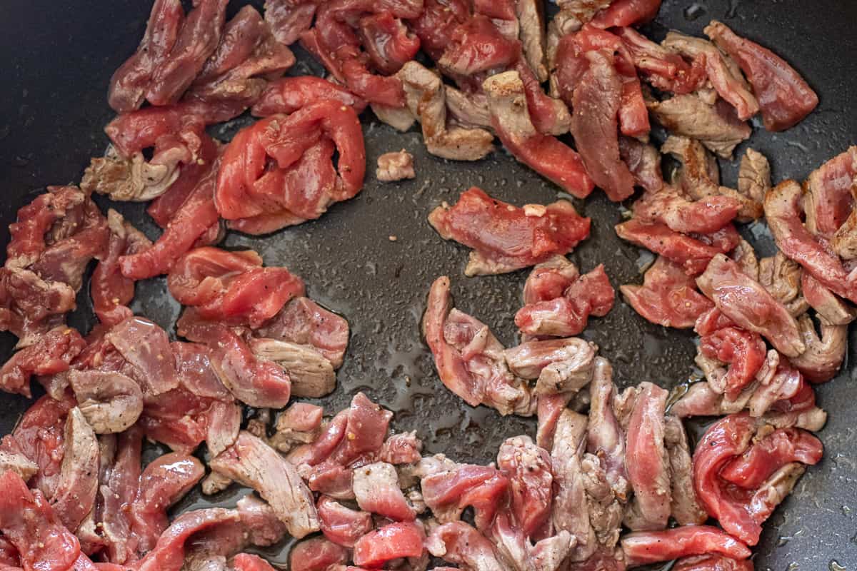 julien cut beef pieces are stir frying in a wok