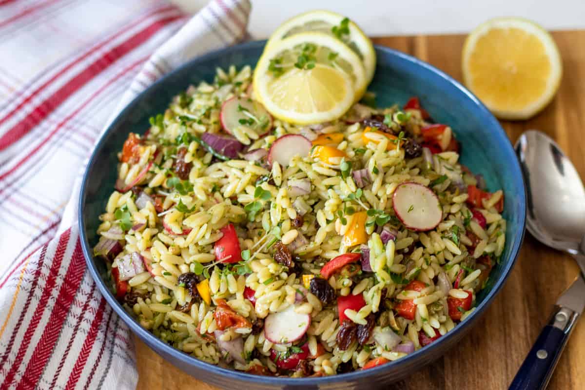 orzo pasta salad served in a bowl with sliced lemons