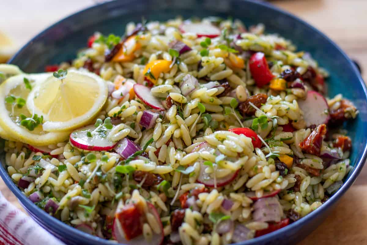 orzo salad served in a bowl and garnished with sliced lemons