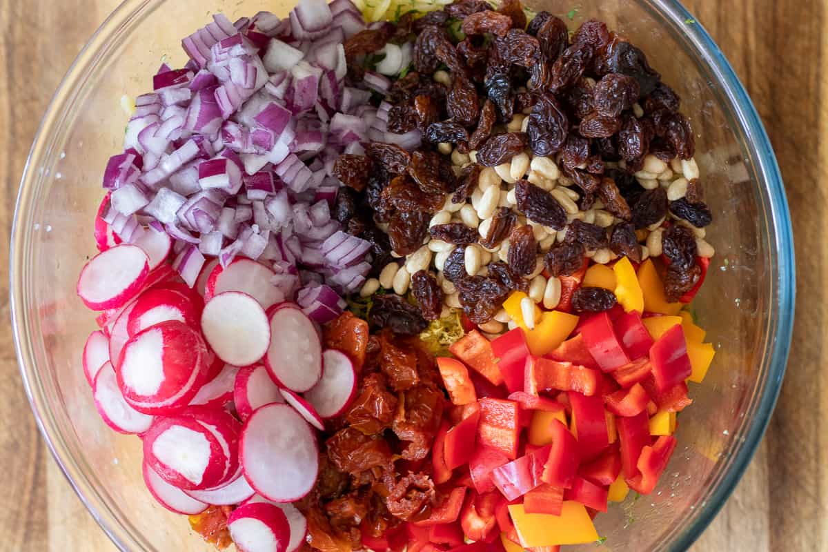sliced radishes, diced peppers and onions, pine nuts and sultanas are added to orzo