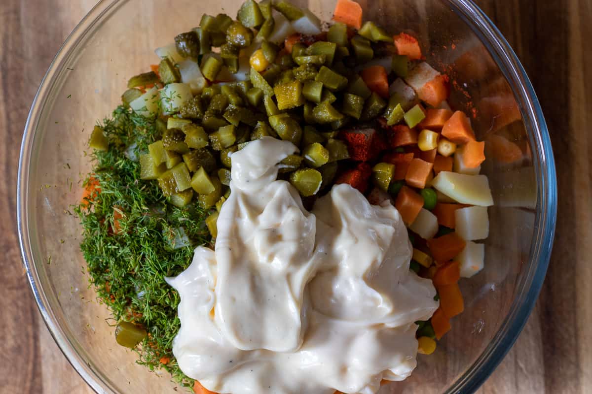 cooked vegetables and chopped herbs and mayonnaise in a bowl