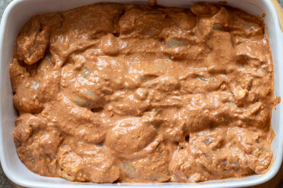 marinated tandoori chicken thighs are placed in an oven dish