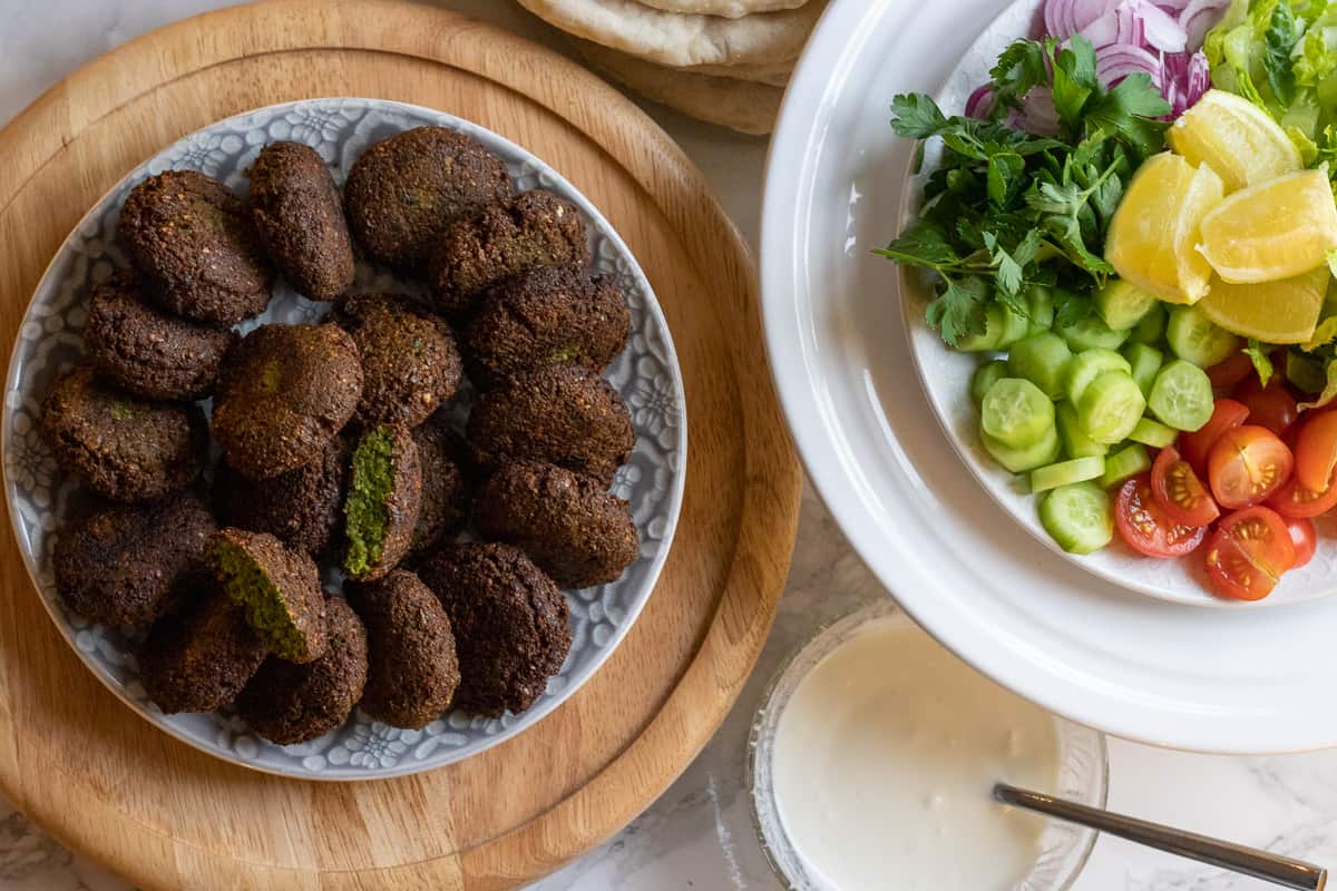 crispy falafels served on a plate along with salad, sauce and pita bread