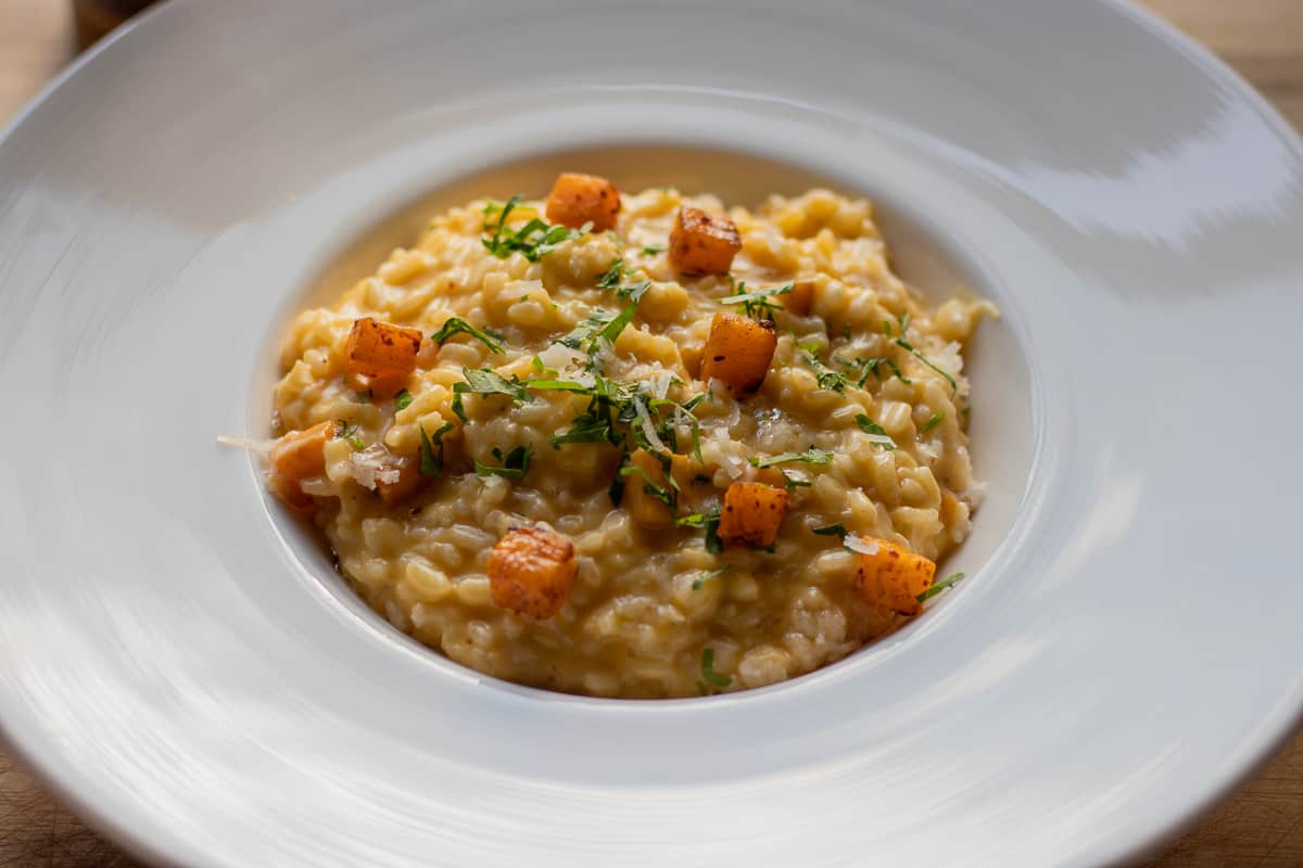 pumpkin risotto with parmesan - risotto Alla zucca served with chopped herbs and parmesan