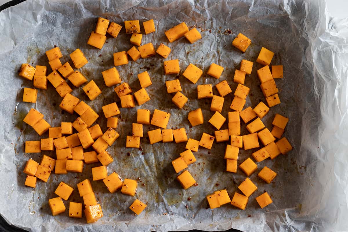small diced pumpkin spread on a baking sheet