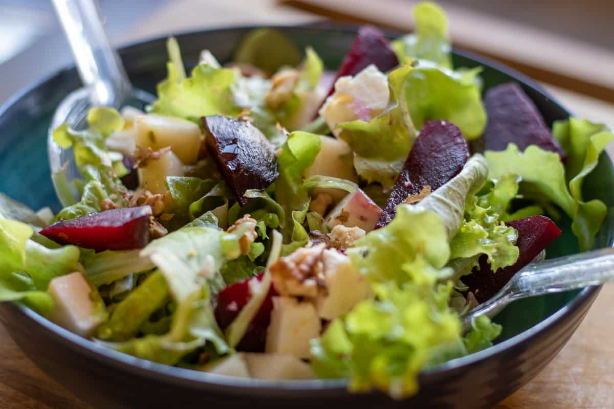 The salad is served in a blue bowl after being dressed with balsamic and olive oil.