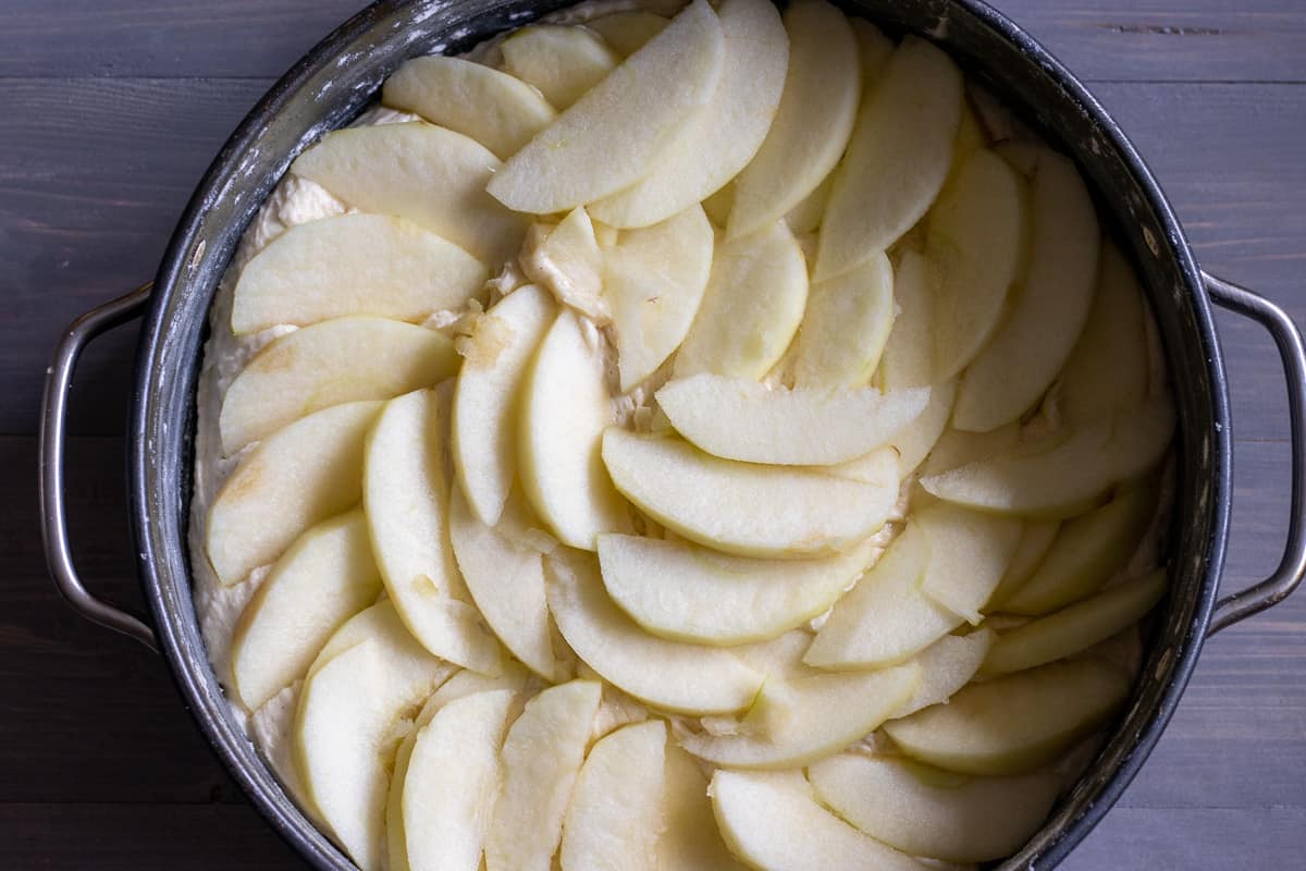 sliced apples are scattered on top of cake batter