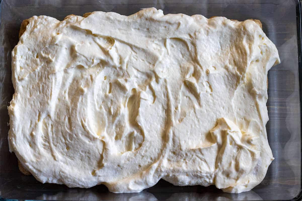 half of the mascarpone filling is spread over ladyfinger biscuits