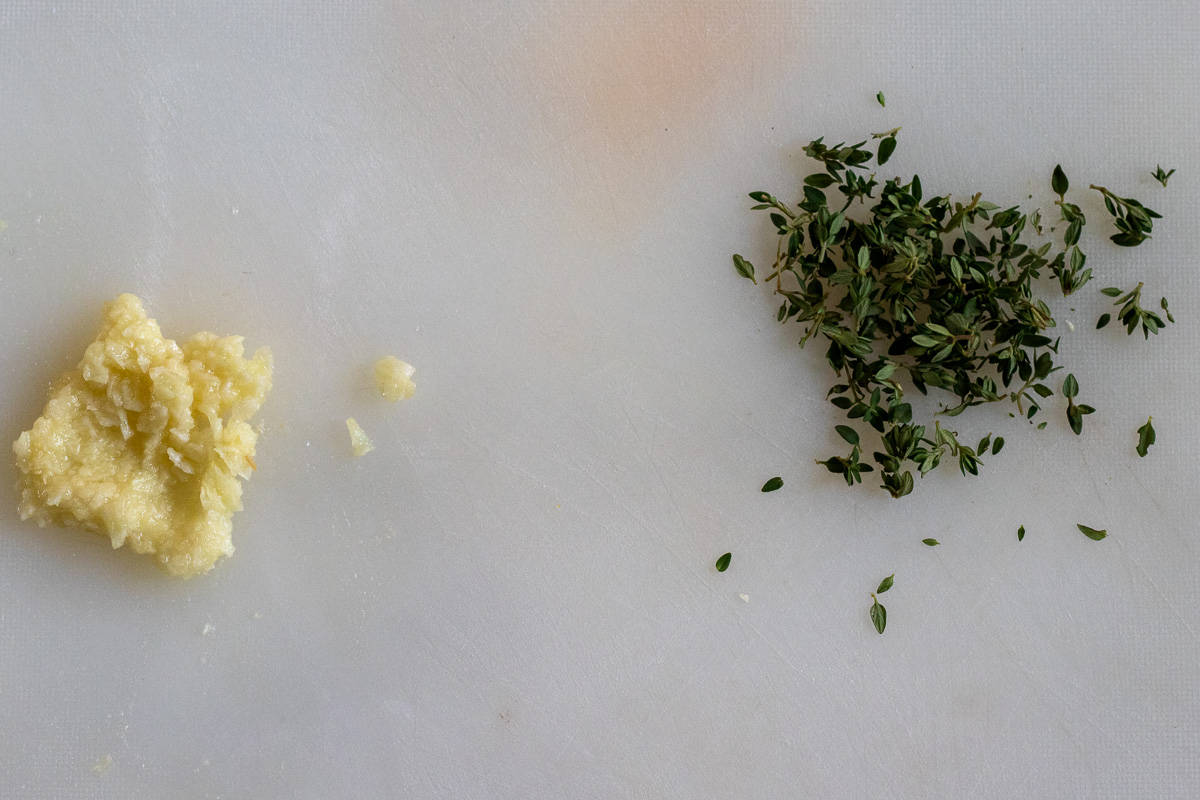 finely chopped garlic and thyme leaves on a cutting board