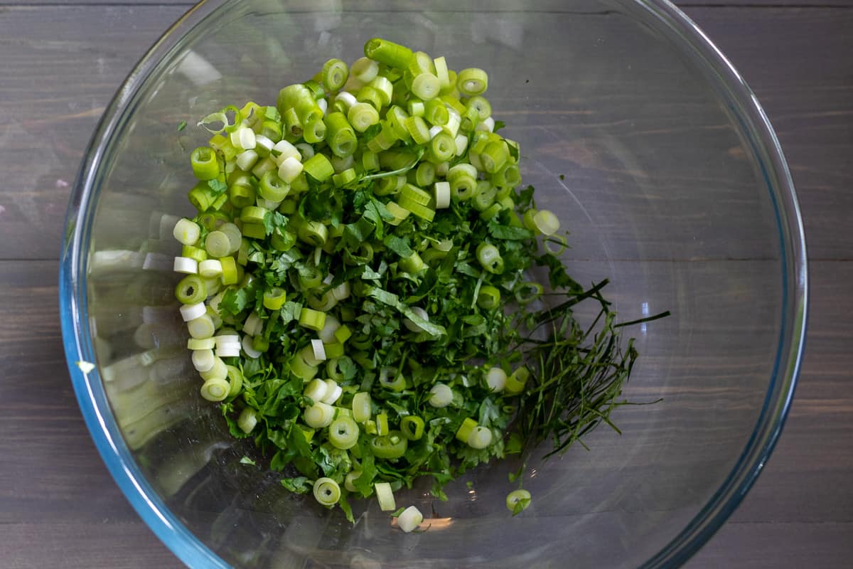 lemongrass, lime leaves, coriander and spring onions are placed in a bowl