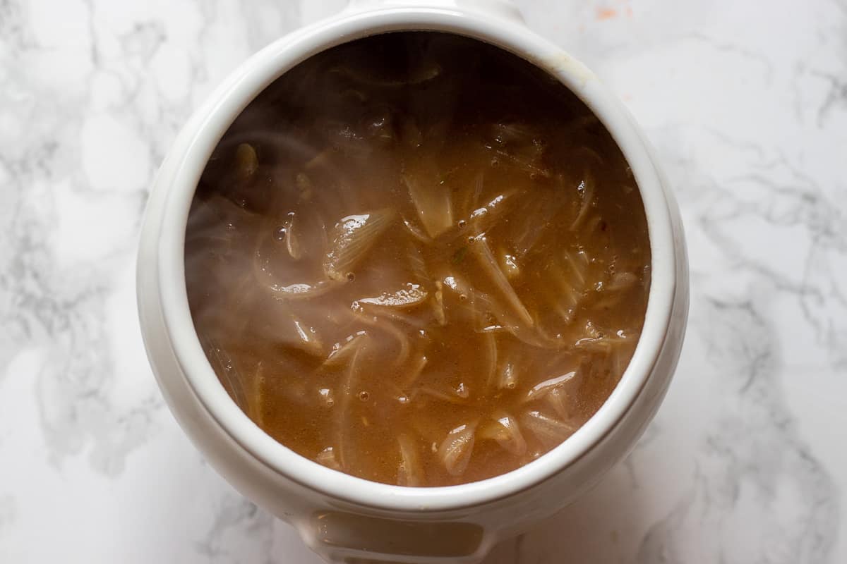 Oven proof soup bowl is filled with French onion soup