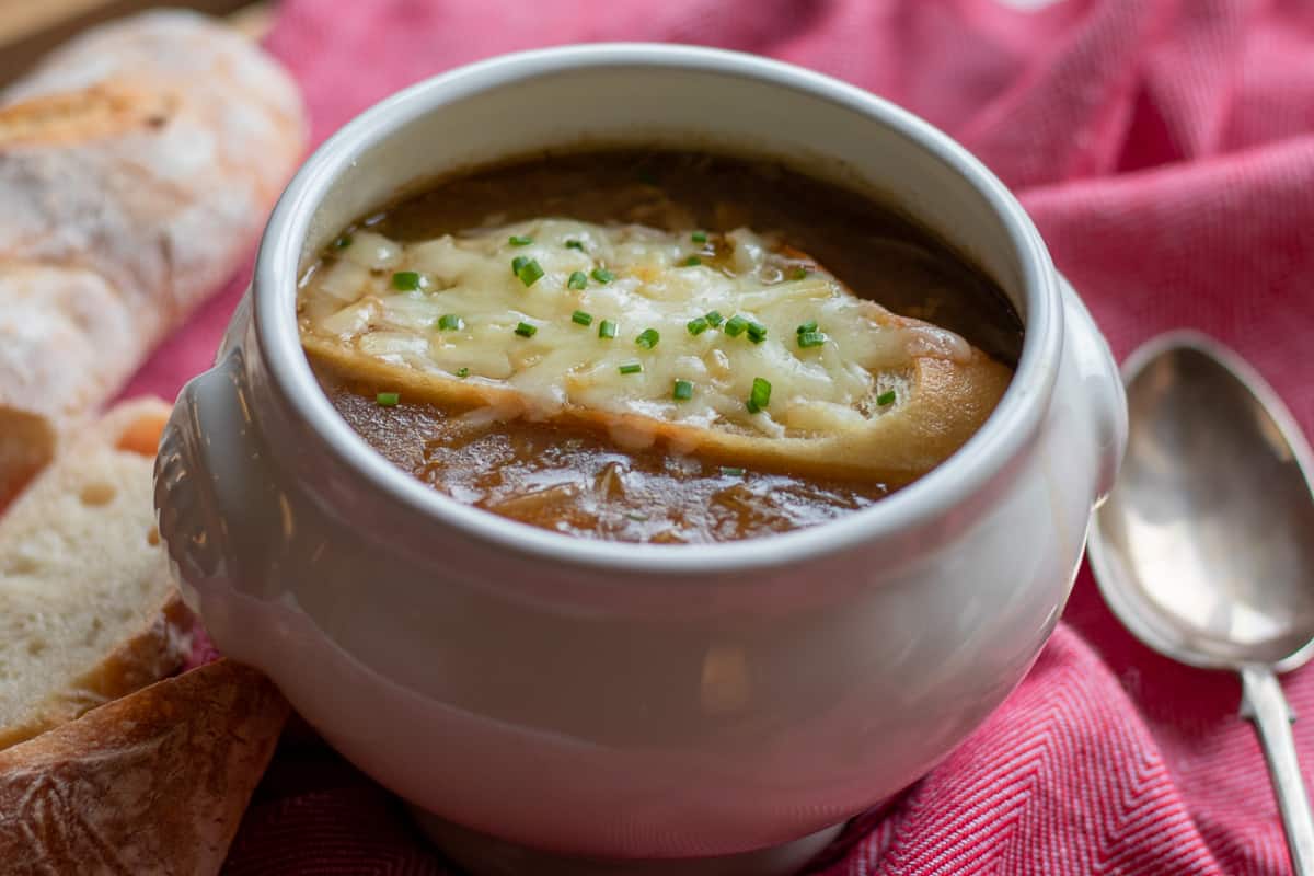 French Onion Soup served with a slice of cheesy baguette
