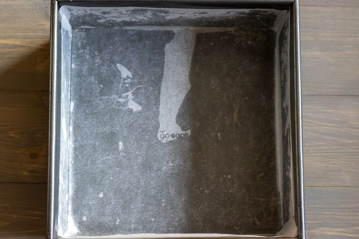 8" square cake tin is lined with parchment paper