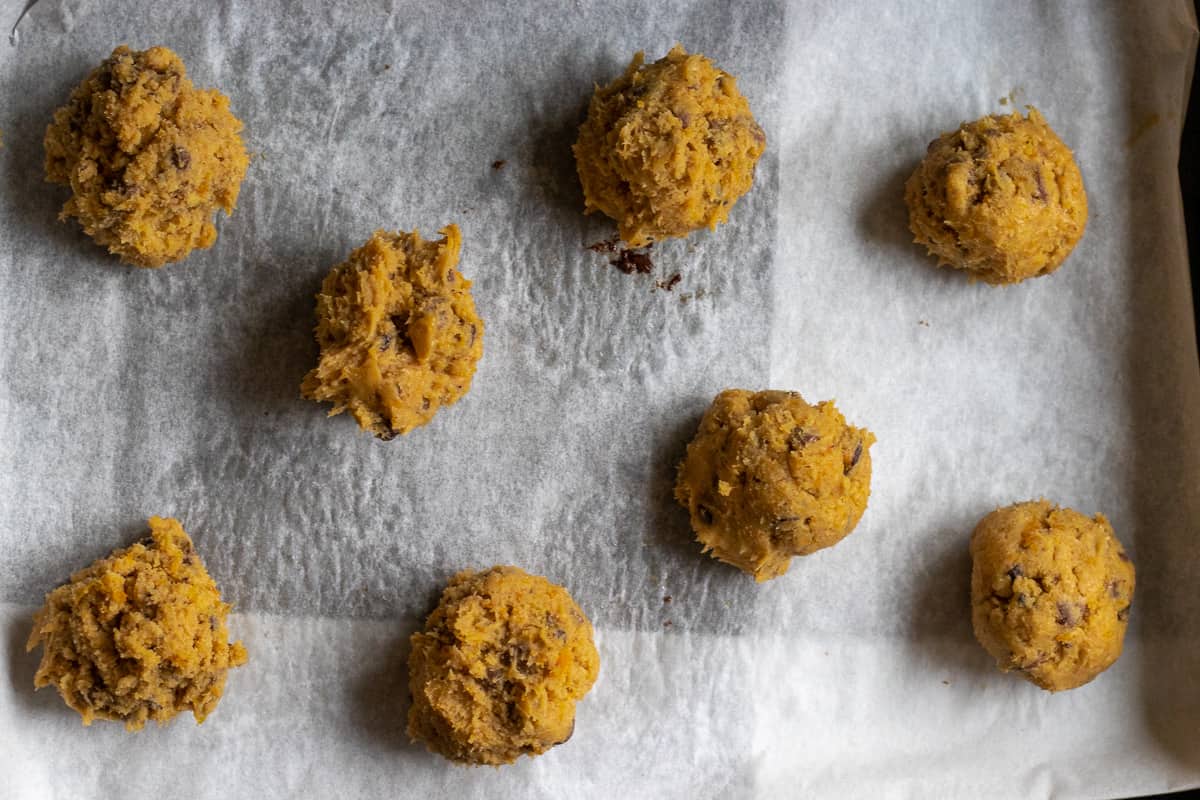 cookie dough balls lined on a baking sheet