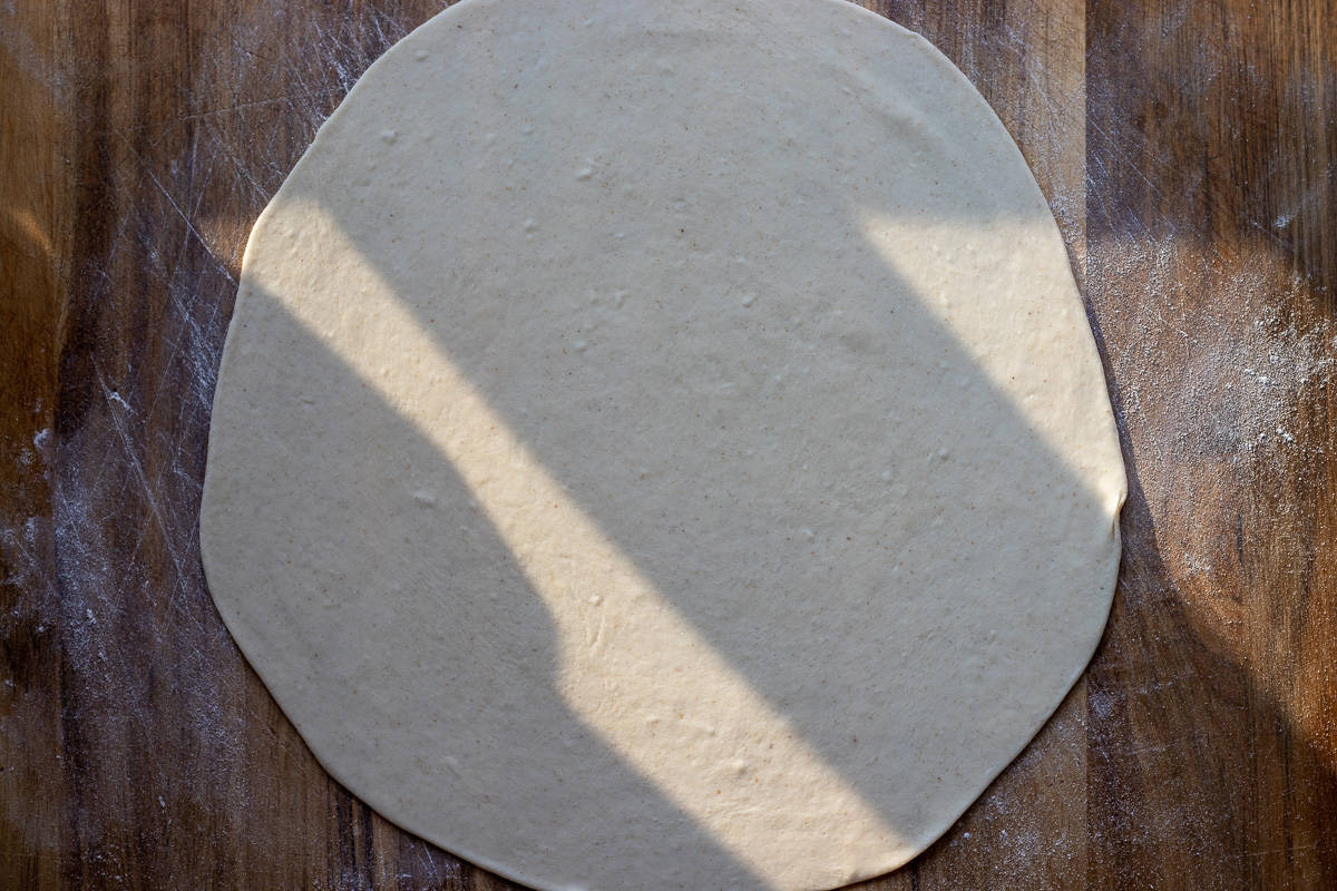 a dough ball is rolled into a large and thin circle