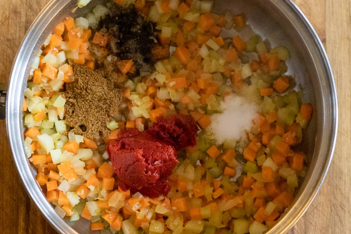 spices, tomato paste and seasoning are added to sautéed vegetables