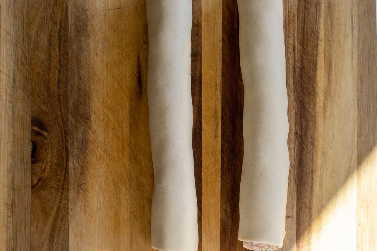 the pastries are rolled over the filling to form a sausage roll shape