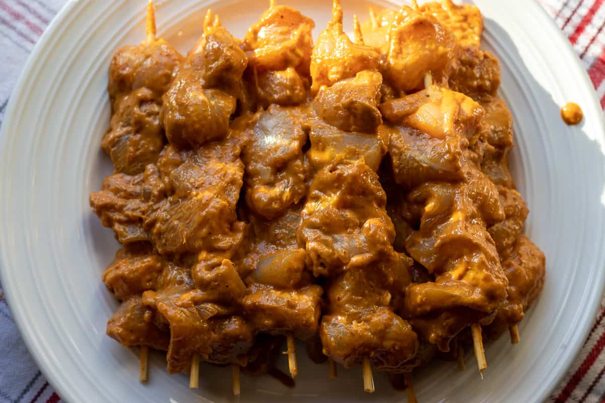 Marinated chicken pieces are threaded onto skewers.