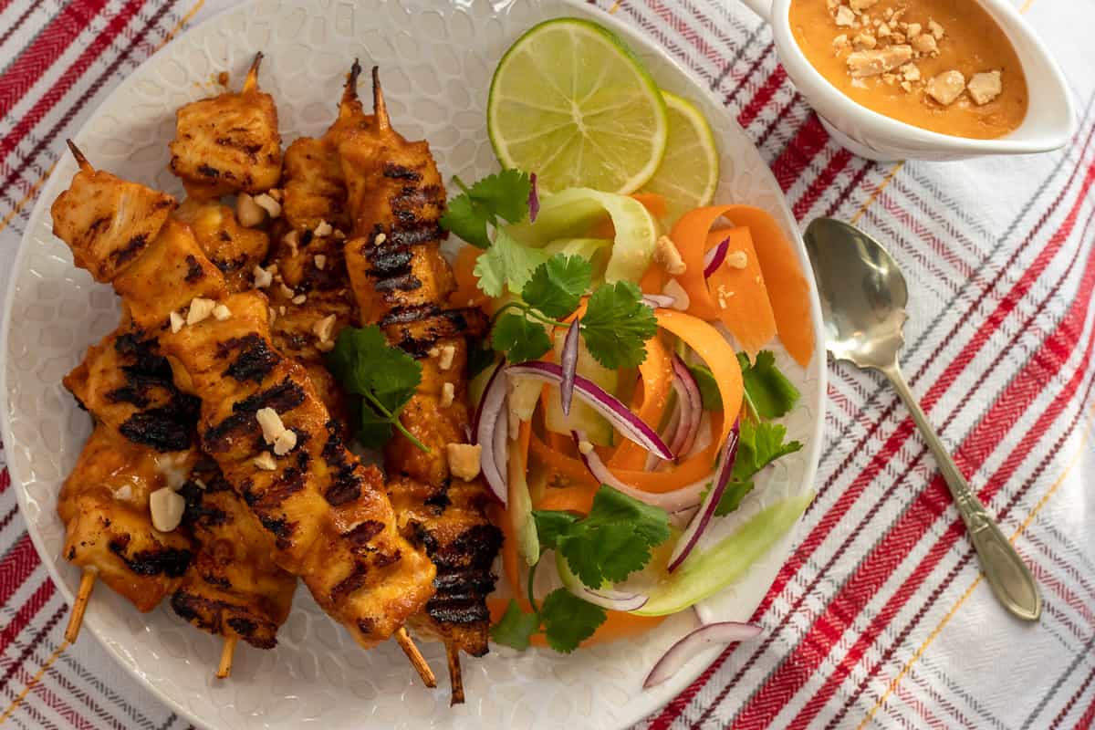Thai chicken skewers are served with salad and peanut sauce.