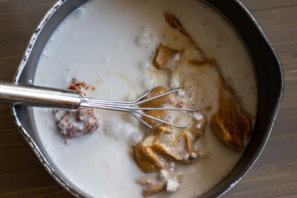 Peanut butter dipping sauce ingredients are placed in a small pan with a whisk.