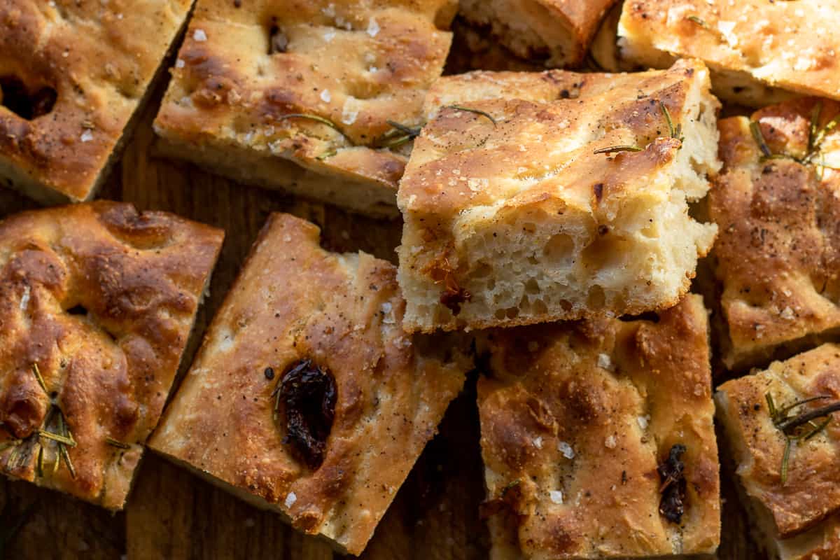 Black pepper sourdough focaccia bread is cut into squares.