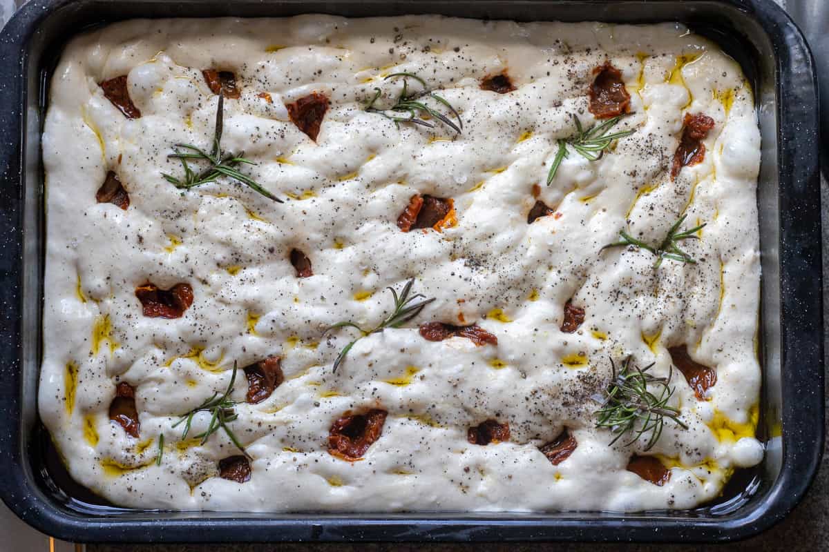 The bread dough is topped with rosemary and sun-dried tomatoes.