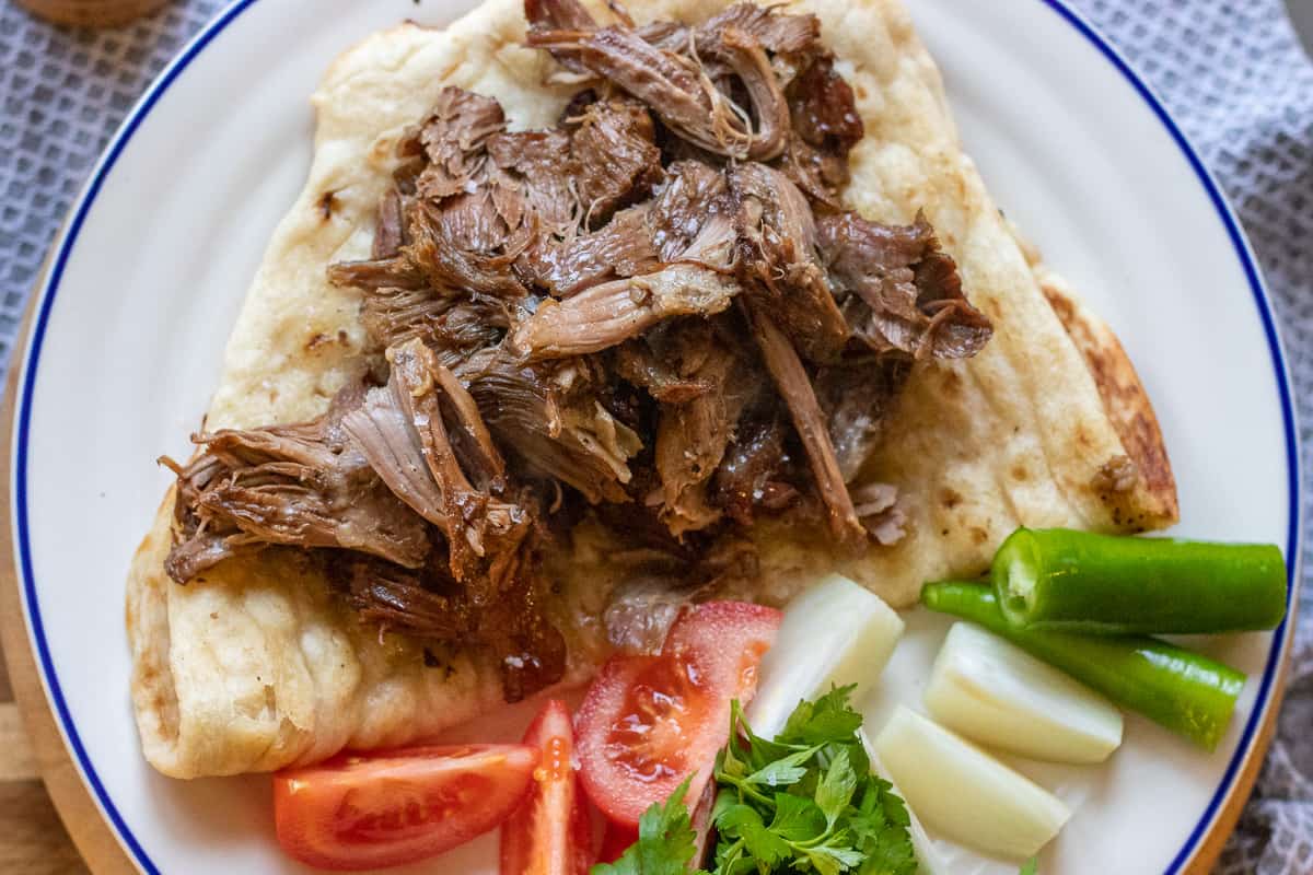 kuzu takdir is traditionally served with onions, peppers and tomato wedges