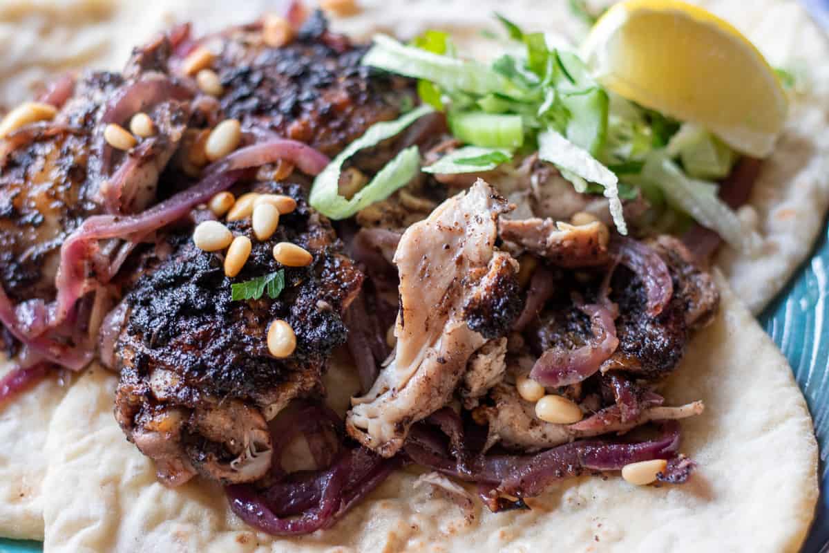 sumac chicken served on pita bread with a piece of lemon wedge