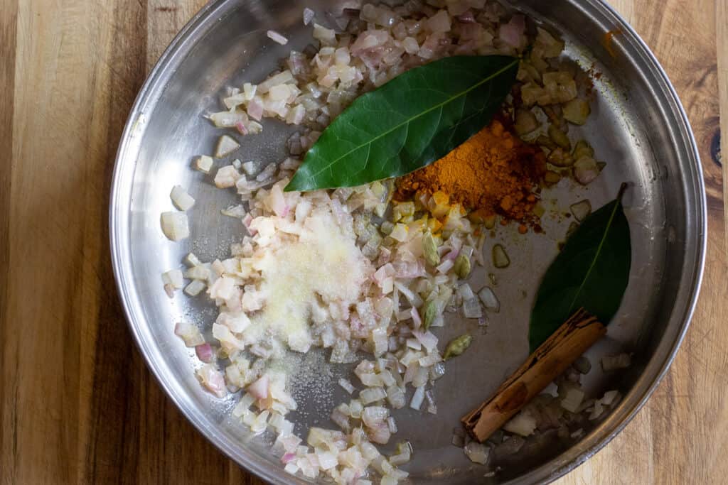 Turmeric, bay leaves, cardamom and cinnamon stick are added to sautéed onions.