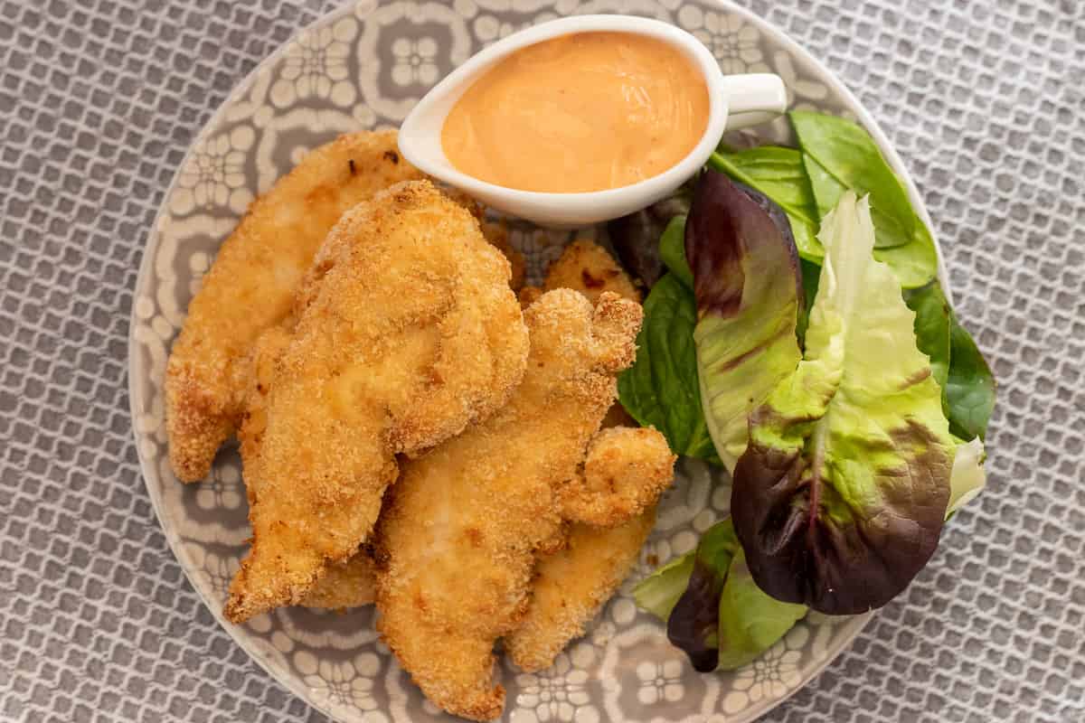 5 pieces of chicken tenders are served with salad and dipping sauce