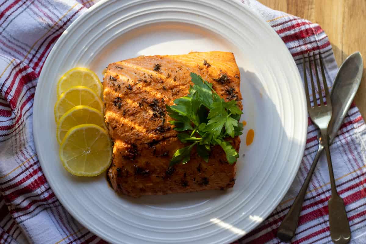 half side of salmon fillet served on a plate with ;lemon slices
