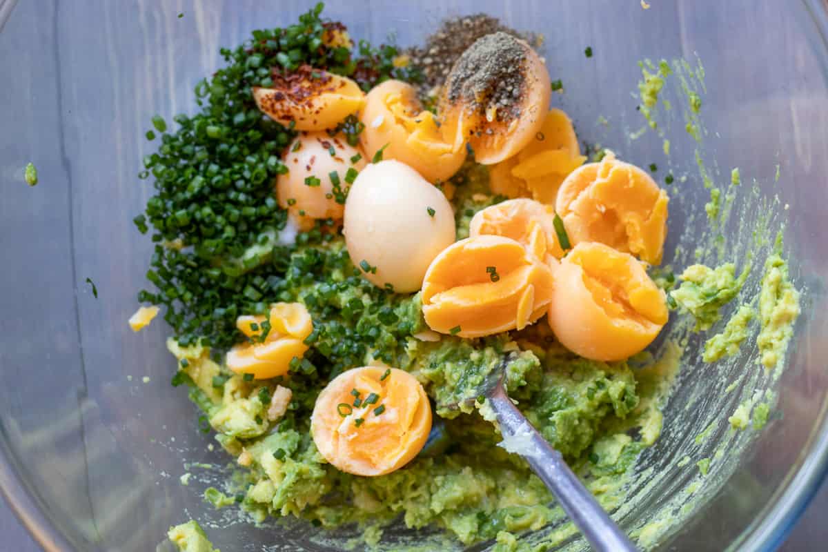 egg yolks are scooped out and added to the avocados