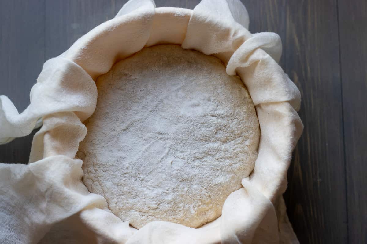the dough has been transferred into a bowl lined with a clean tea towel