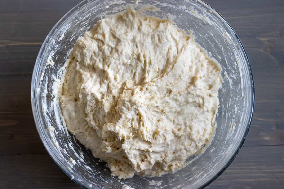 sourdough starter, water, honey and flour are mixed in a bowl to form a dough