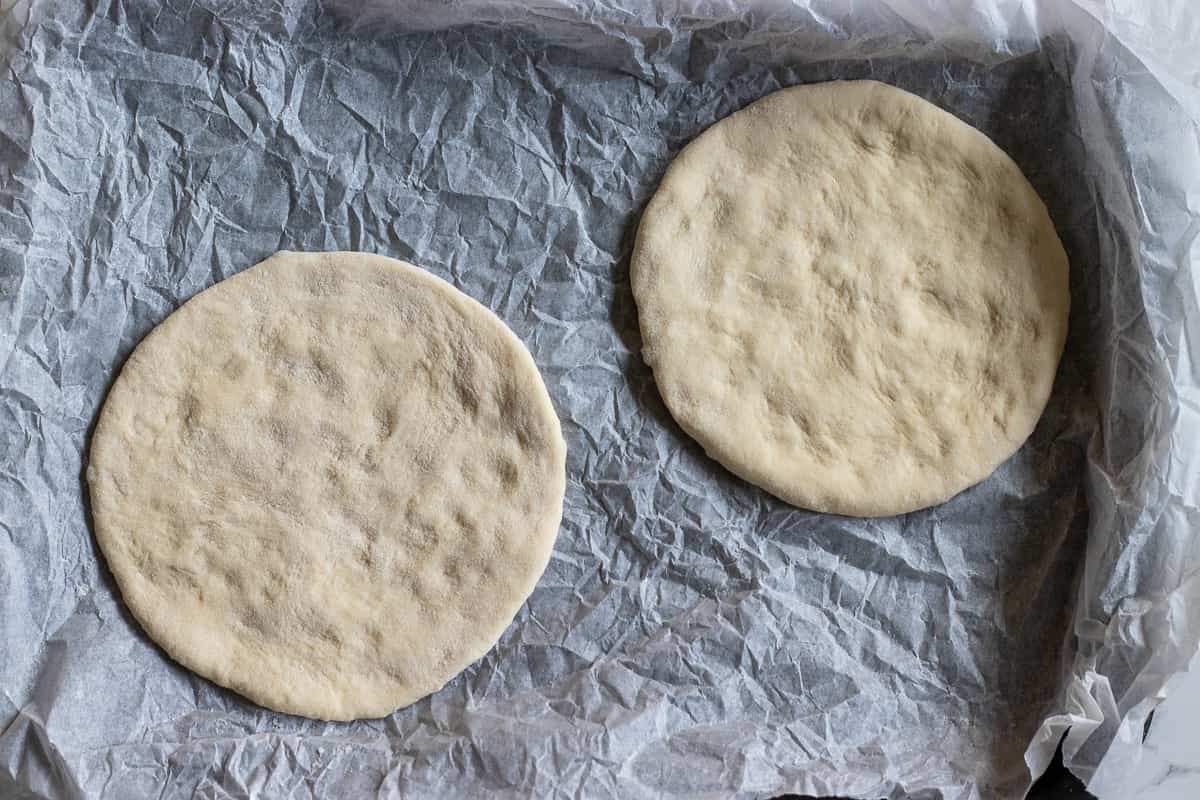 2 dough balls are turned into circles and placed on a tray