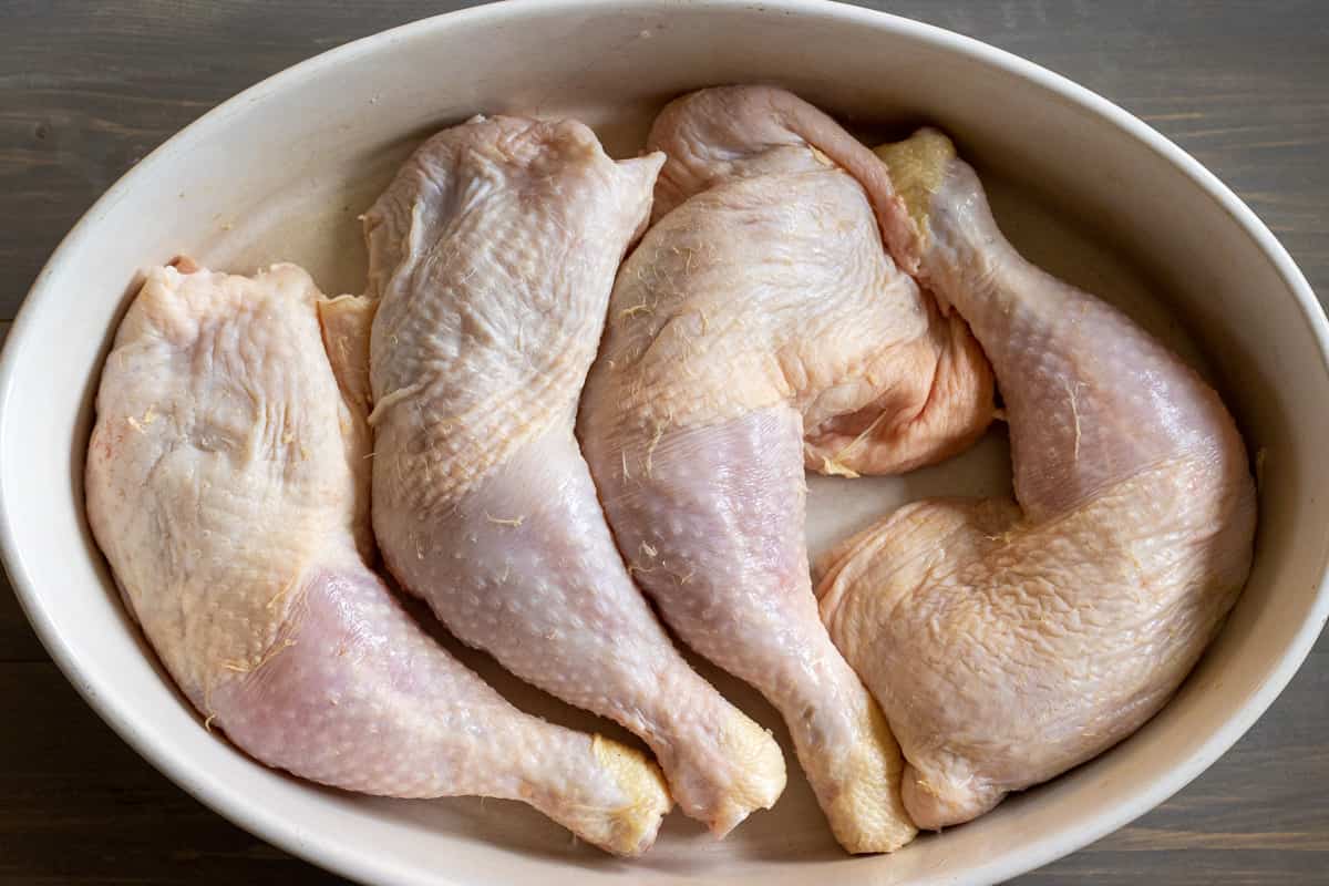 4 pieces of chicken legs are prepped and placed on a tray