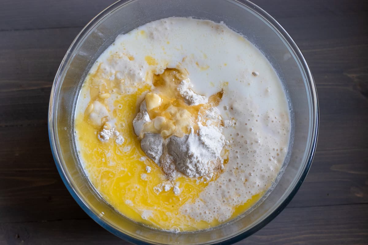 Melted butter, milk, sourdough starter, flour, honey and salt are placed in a glass bowl.
