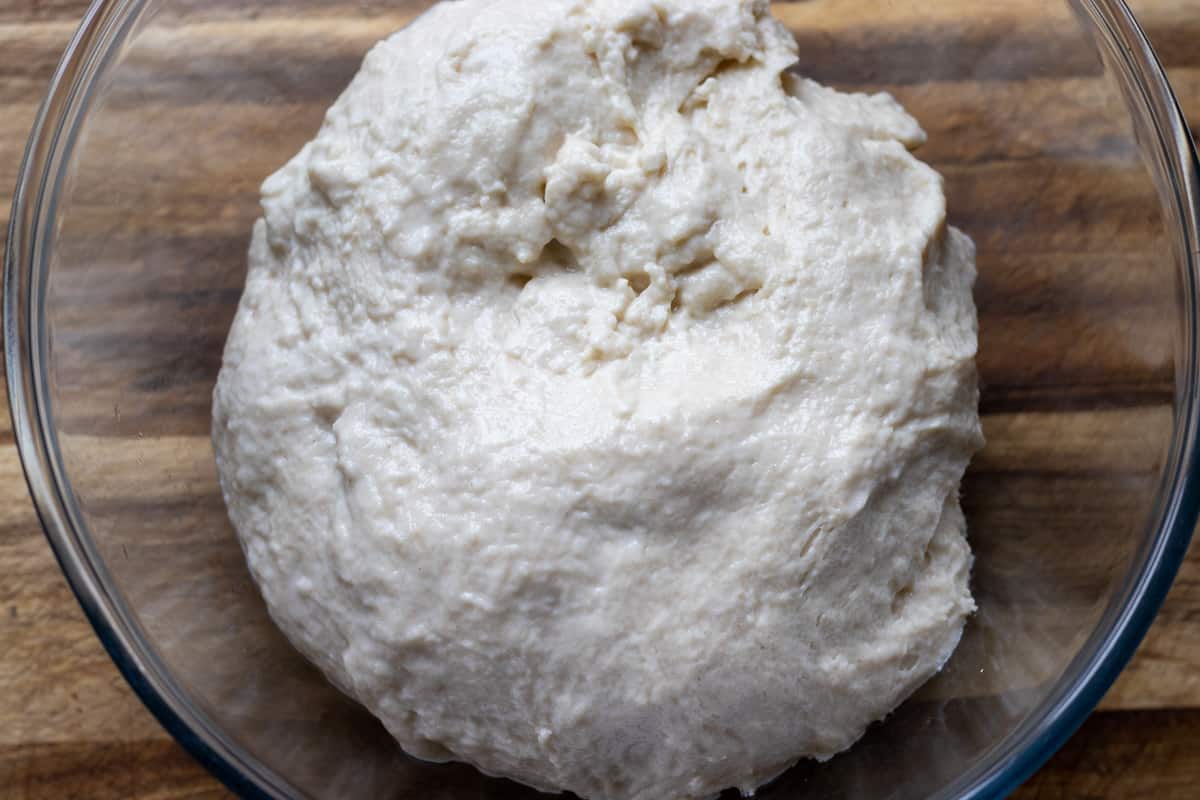 The dough has been placed in a clean glass bowl for resting.