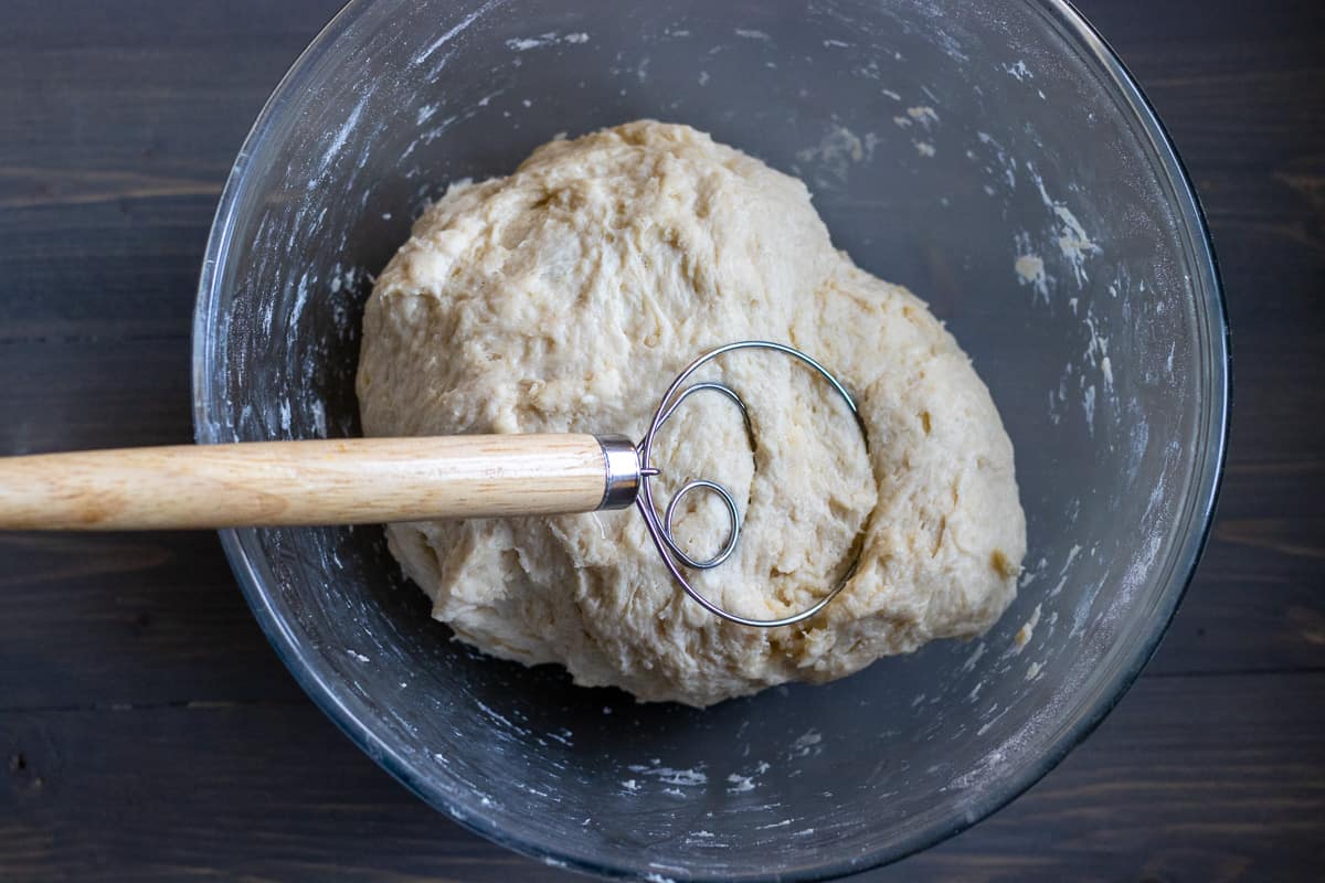 A soft but sticky dough has formed using a dough mixer.