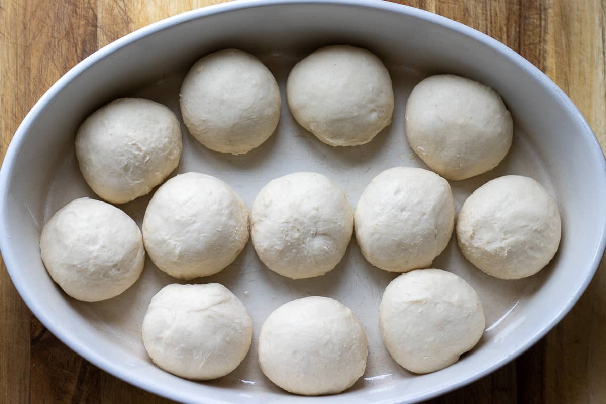 12 pieces of dough balls are placed in a baking dish.